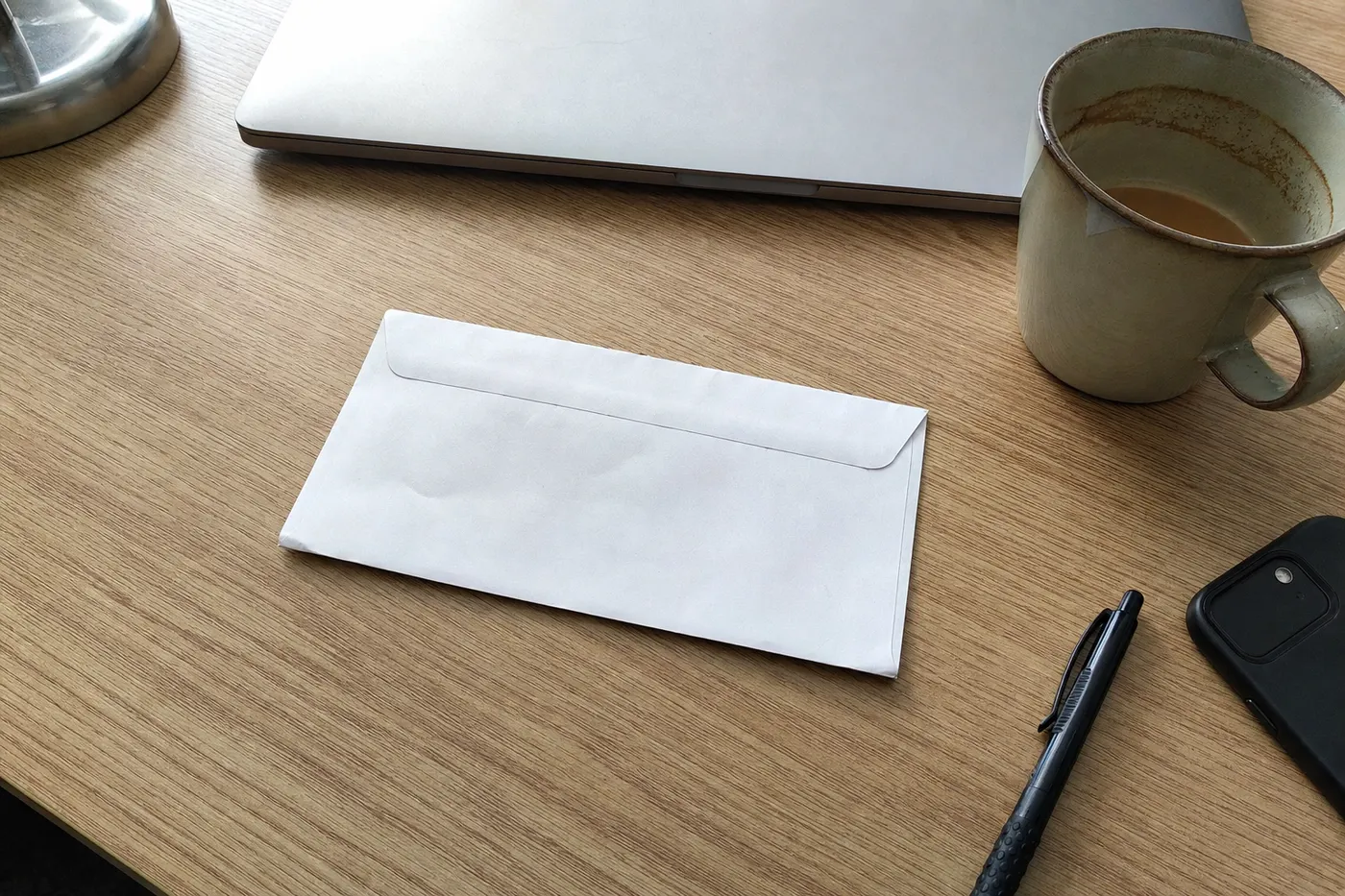 Enveloppe blanche posée sur un bureau, à côté d'un ordinateur et d'un café